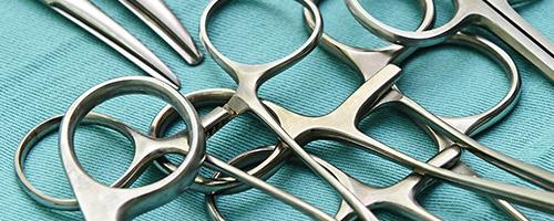 Surgical clamps and scissors arranged on a sterile blue cloth in a medical environment