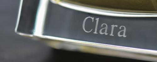 Perfume engraving of the name ‘Clara’ on the bottom of a transparent glass perfume bottle