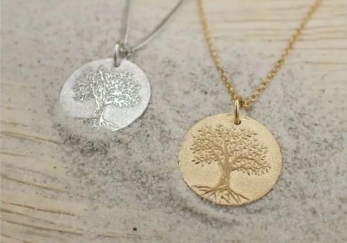 Gold and silver tree of life engraved medallion necklaces on textured background